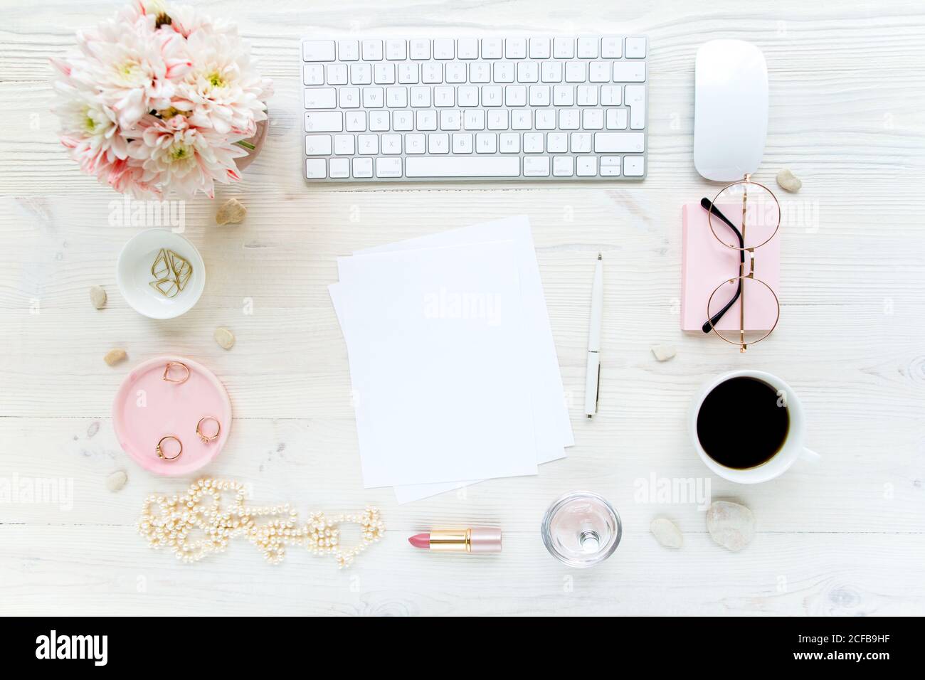 Spazio di lavoro con, computer, carta bianca, crisantemo. Accessori moda donna su sfondo bianco di legno. Riviste, media. Disposizione piatta, vista dall'alto Foto Stock