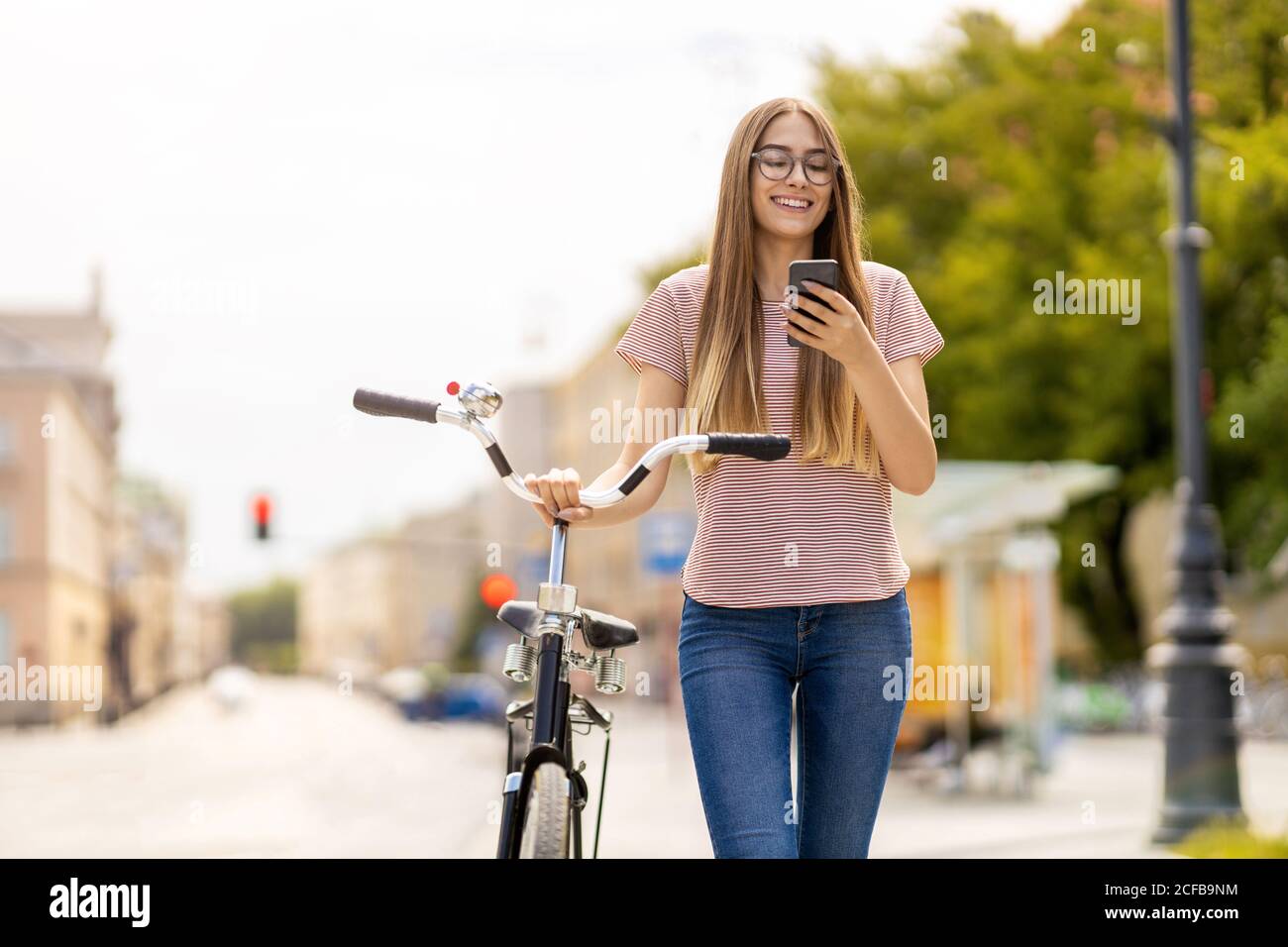 Giovane donna con la bicicletta in città Foto Stock