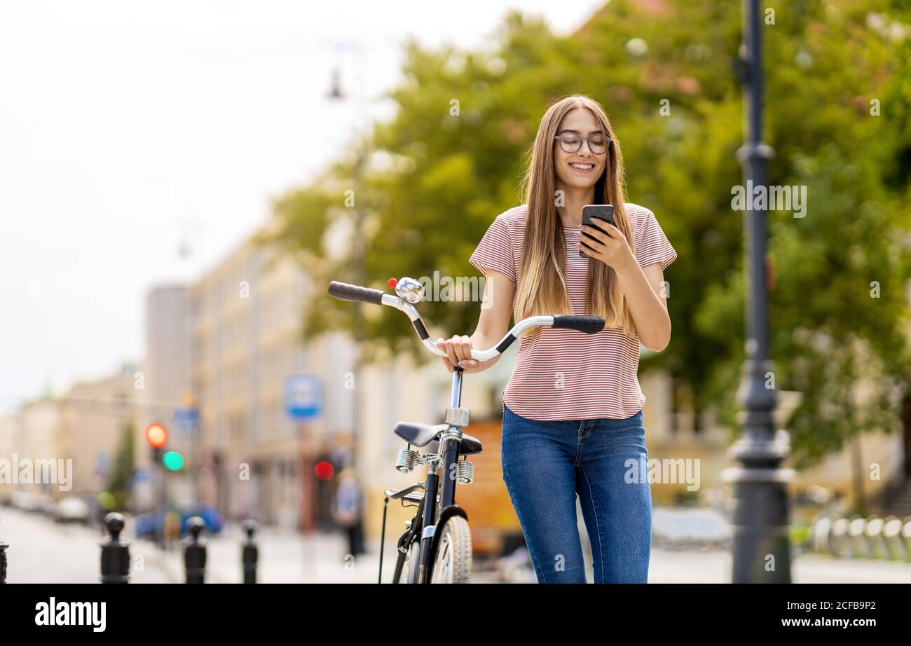 Giovane donna con la bicicletta in città Foto Stock