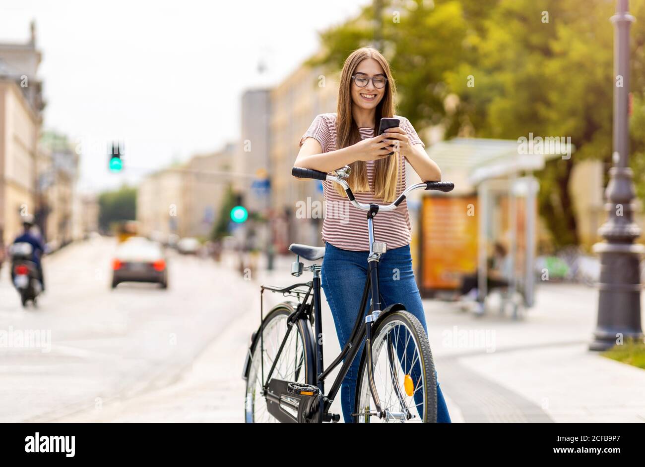 Giovane donna con la bicicletta in città Foto Stock