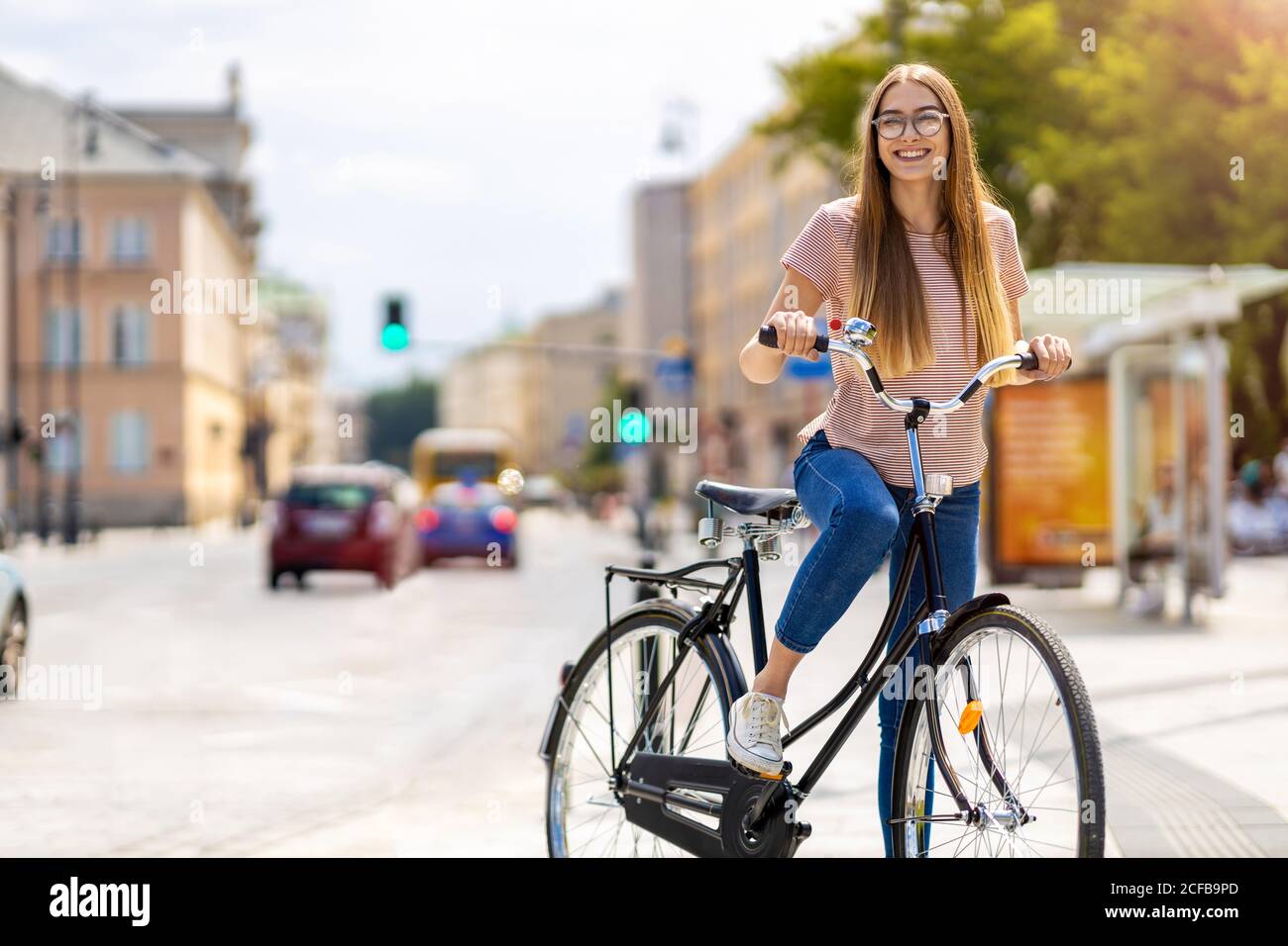 Giovane donna con la bicicletta in città Foto Stock