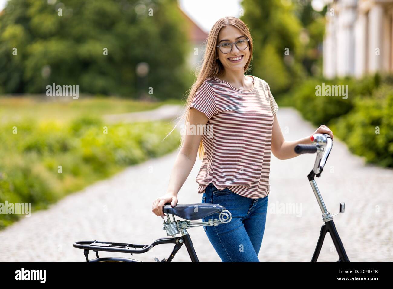 Giovane donna con la bicicletta in città Foto Stock
