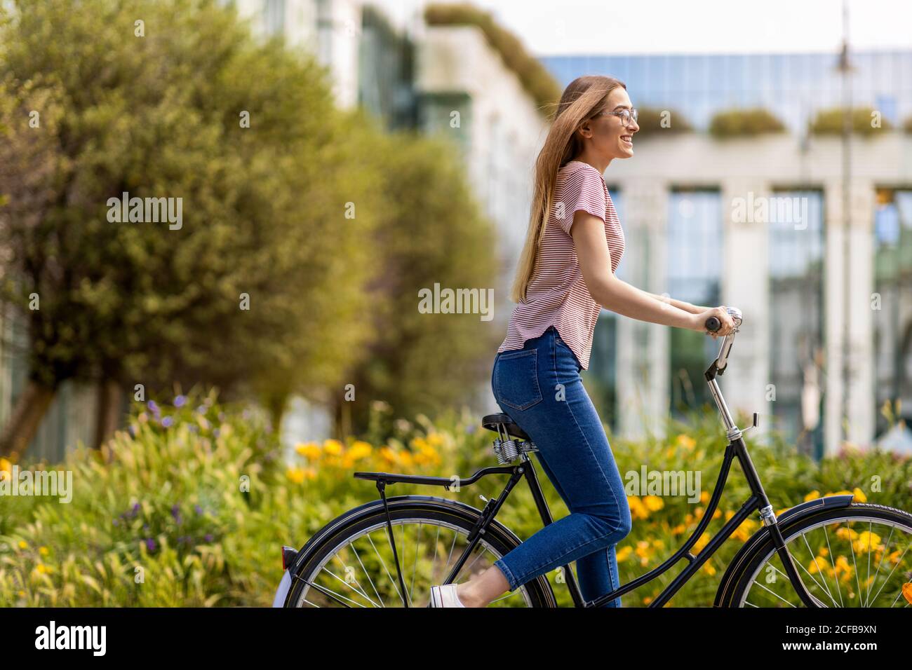 Giovane donna con la bicicletta in città Foto Stock