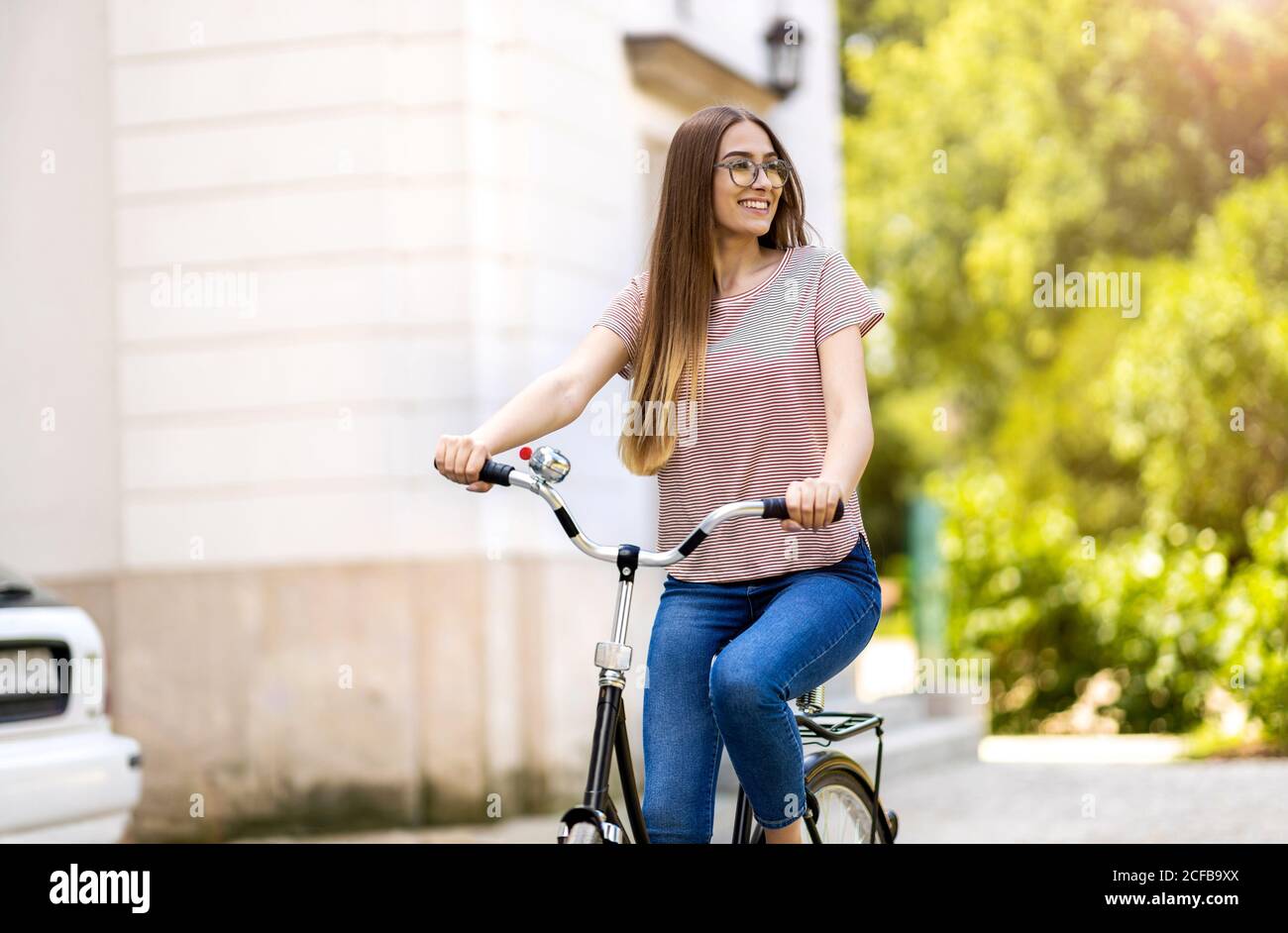 Giovane donna con la bicicletta in città Foto Stock