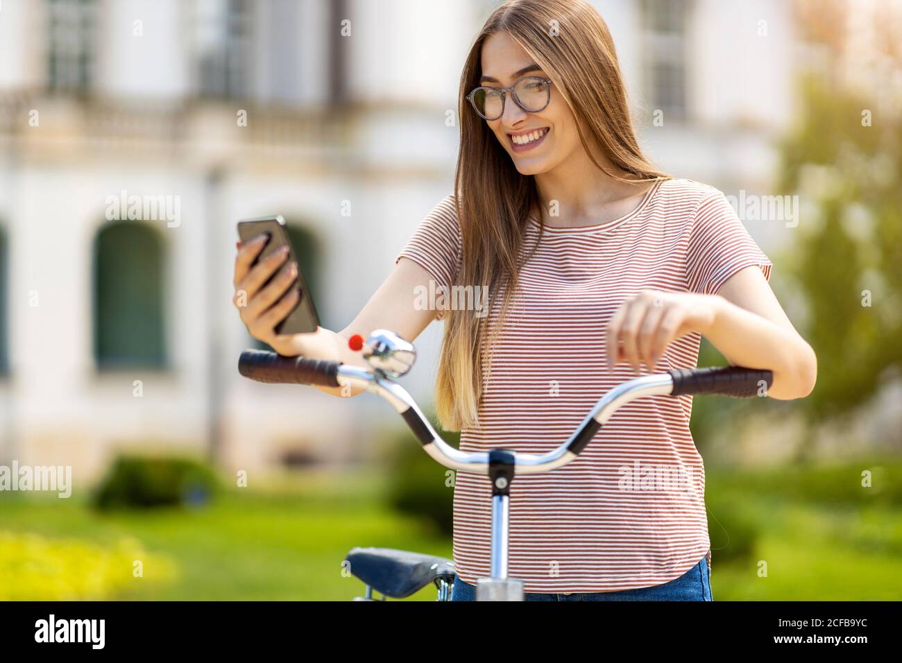 Giovane donna con la bicicletta in città Foto Stock