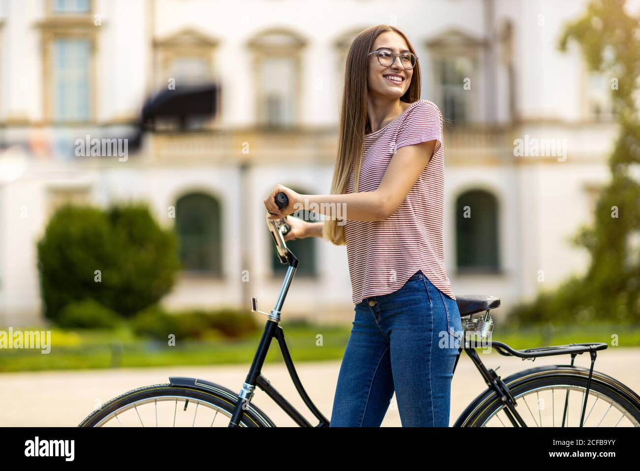 Giovane donna con la bicicletta in città Foto Stock