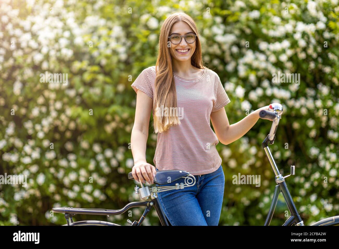 Giovane donna con la bicicletta in città Foto Stock