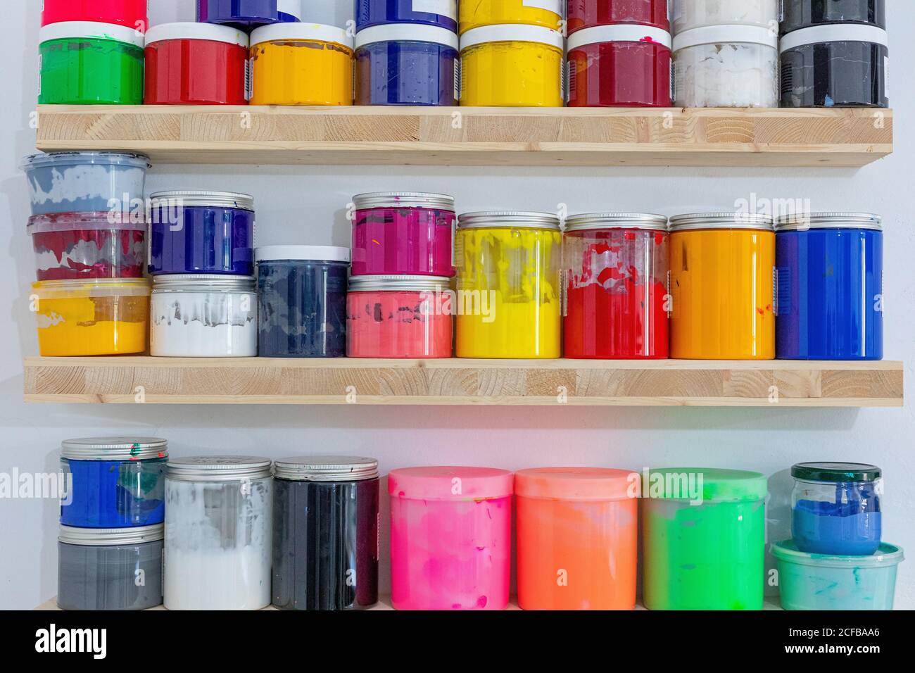 Ripiani con tini colorati di vernice di diverse dimensioni e colore sul luogo di lavoro Foto Stock