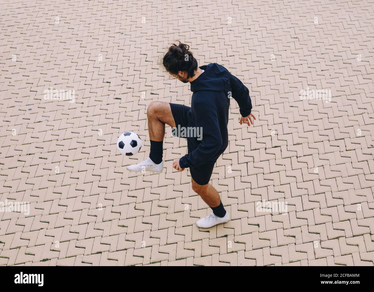Sportivo calcia palla da calcio con ginocchio Foto Stock