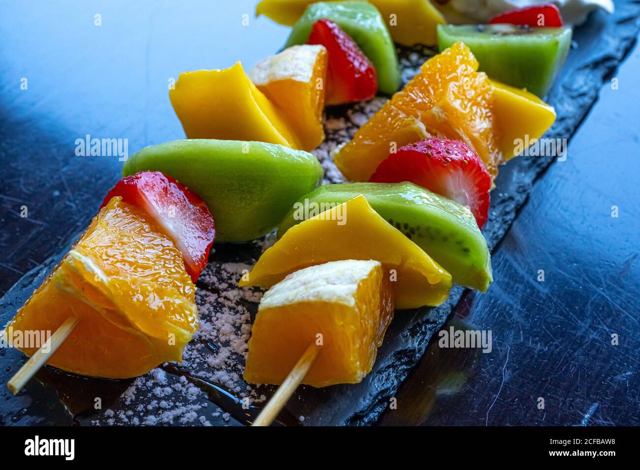 Kebab di frutta fatto di arance, fragole, Kiwi, Mango. Primo piano della macro. Messa a fuoco selettiva Foto Stock