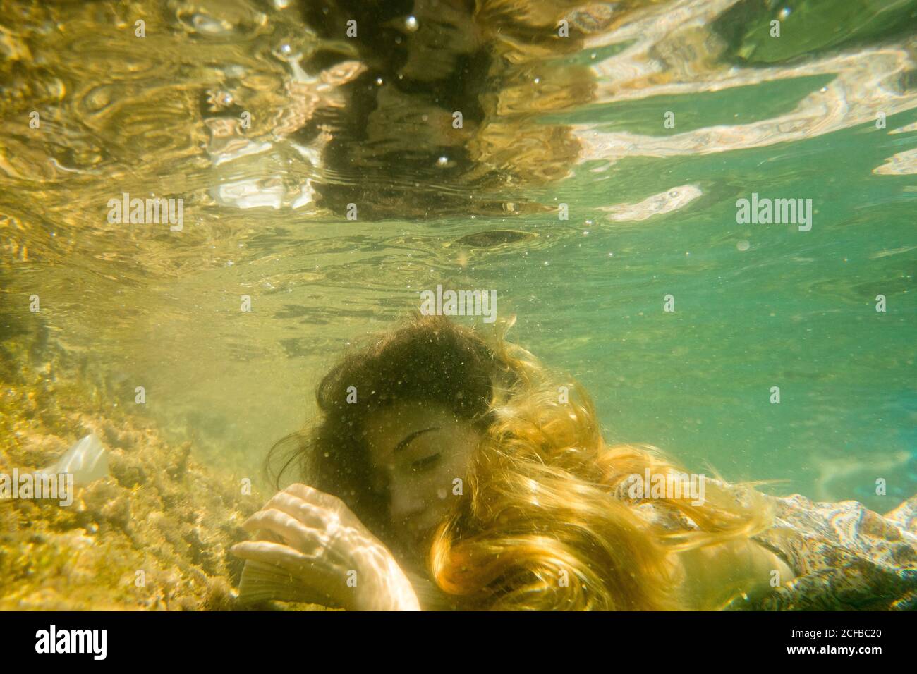 Una donna dorme e sogna sott'acqua appoggiandosi alla testa un libro Foto Stock