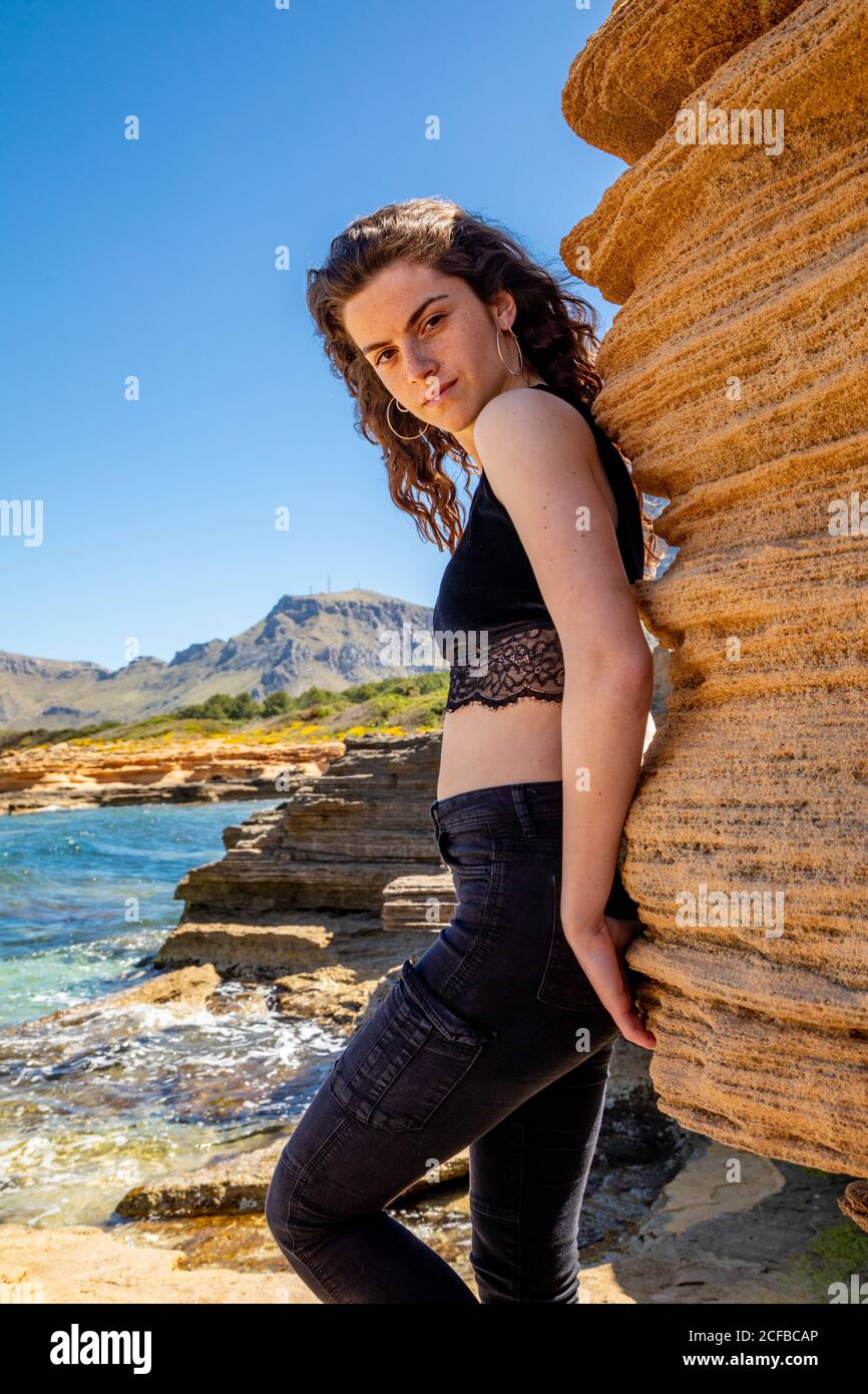 Vista laterale di Slim Woman in nero crop top e jeans in piedi nel canyon e godere del paesaggio Foto Stock