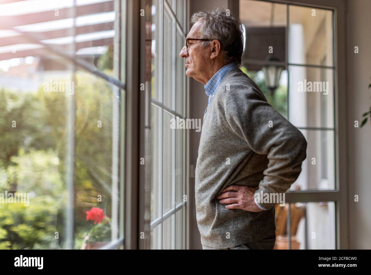 Senior uomo guardando fuori della finestra a casa Foto Stock