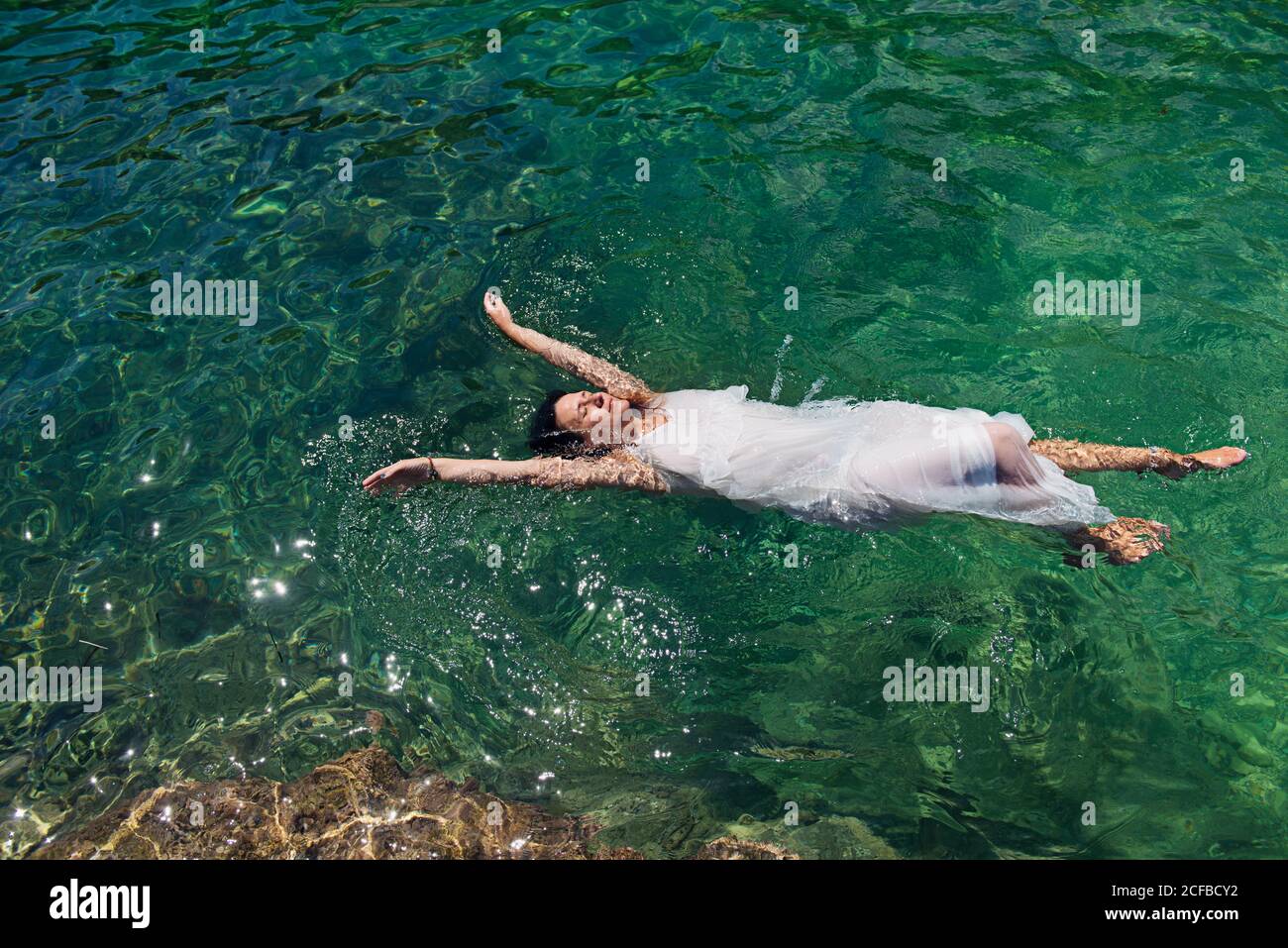 Una donna galleggia in mare con una rosa in mano, fingendo di essere annegata Foto Stock