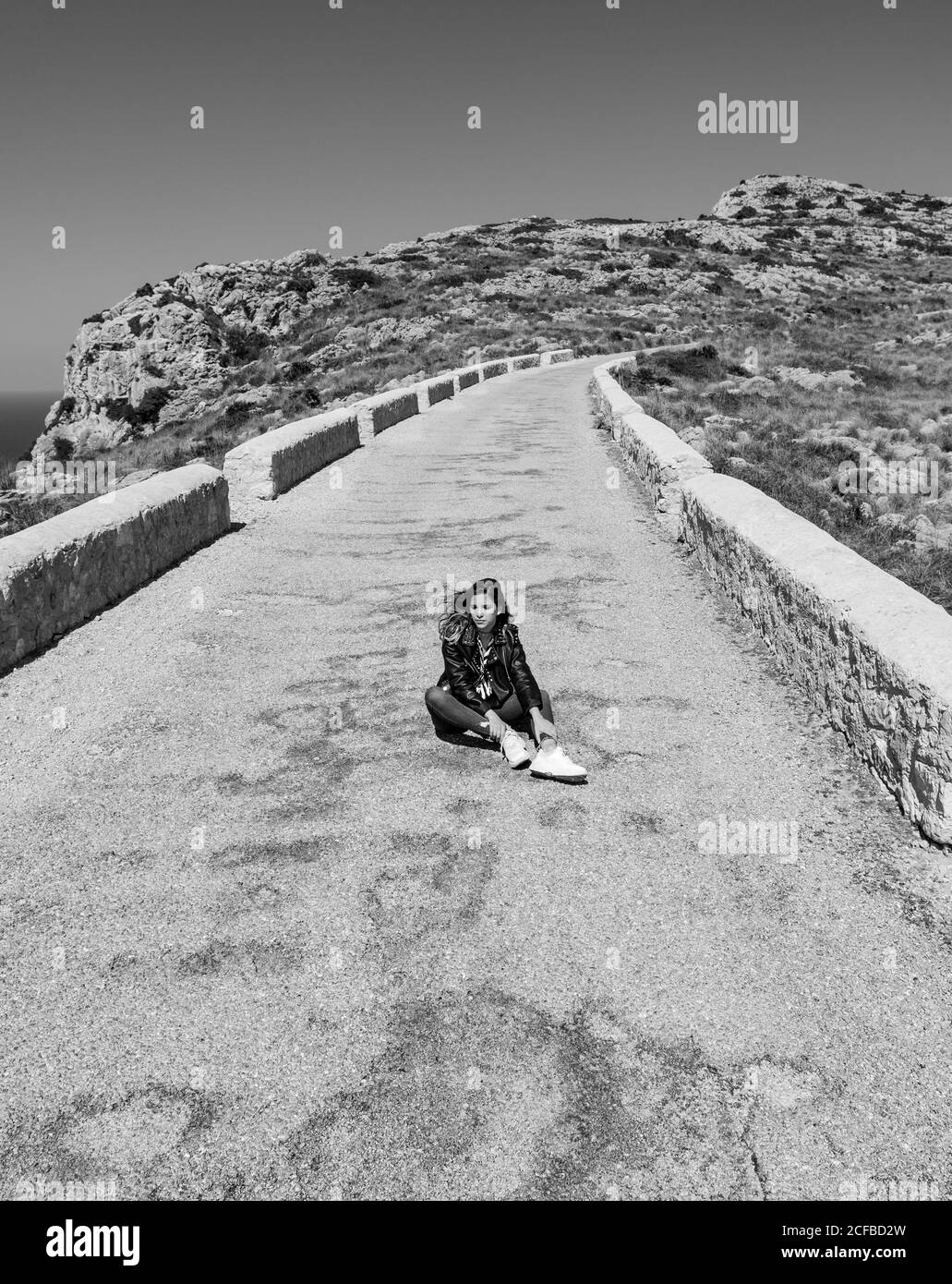 Donna seduta su un sentiero in pietra in campagna Foto Stock