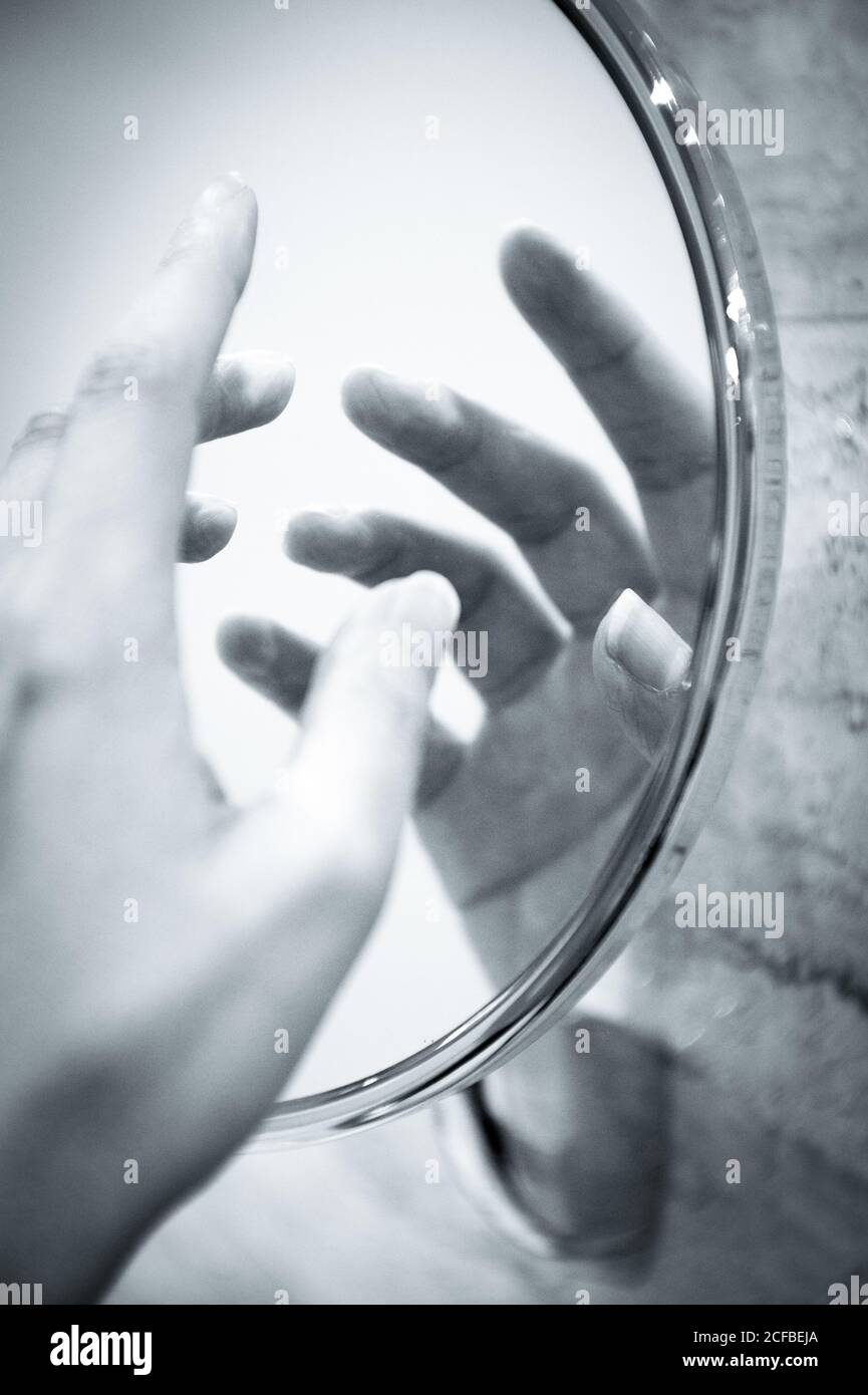 Mano femminile riflessa nello specchio rotondo. Scena misteriosa Foto stock  - Alamy