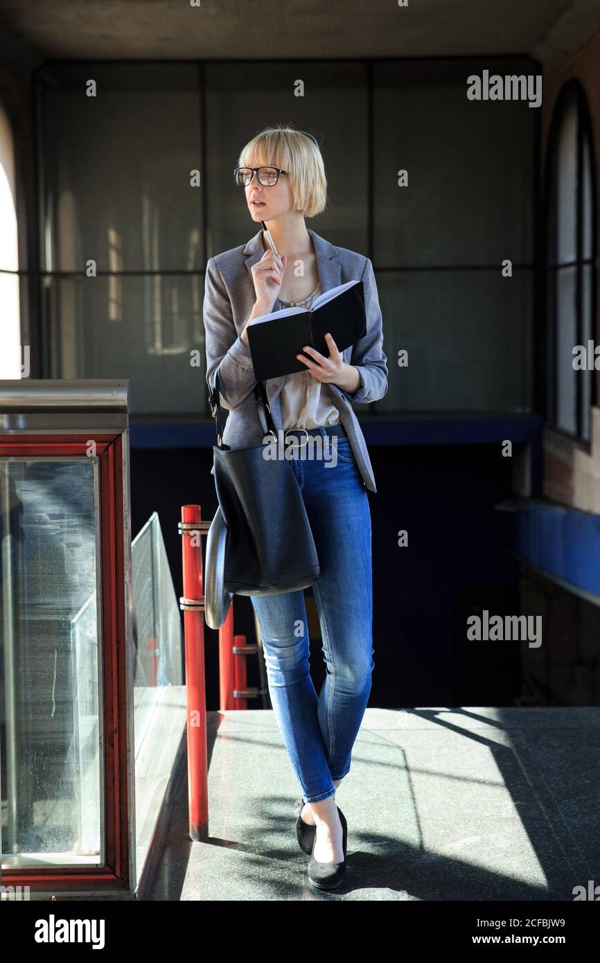 Donna d'affari bionda che cammina con il blocco note Foto Stock