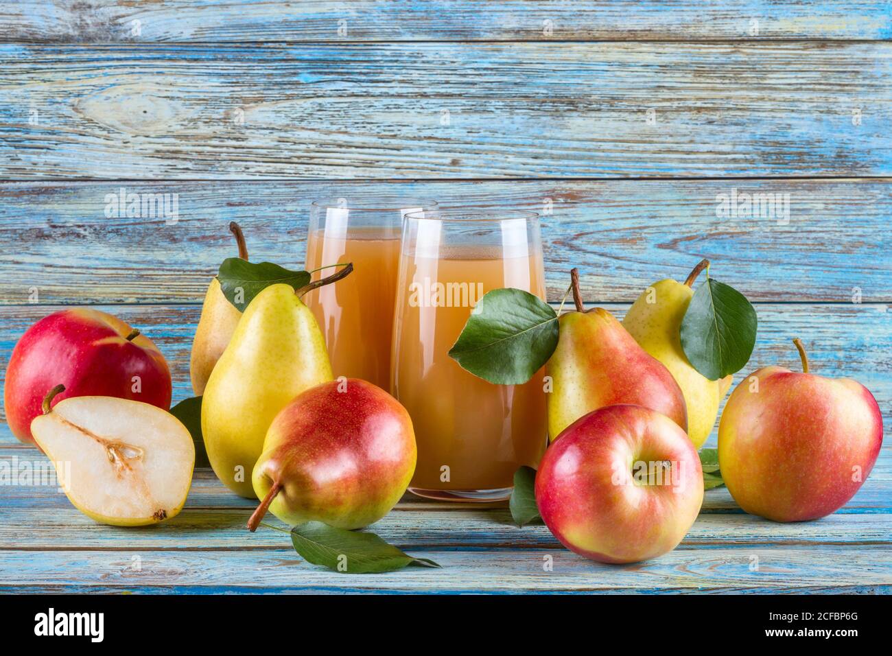 Succo di pera-mela fresco biologico in vetro con intero grezzo pere e mele a fette su sfondo legnoso Foto Stock