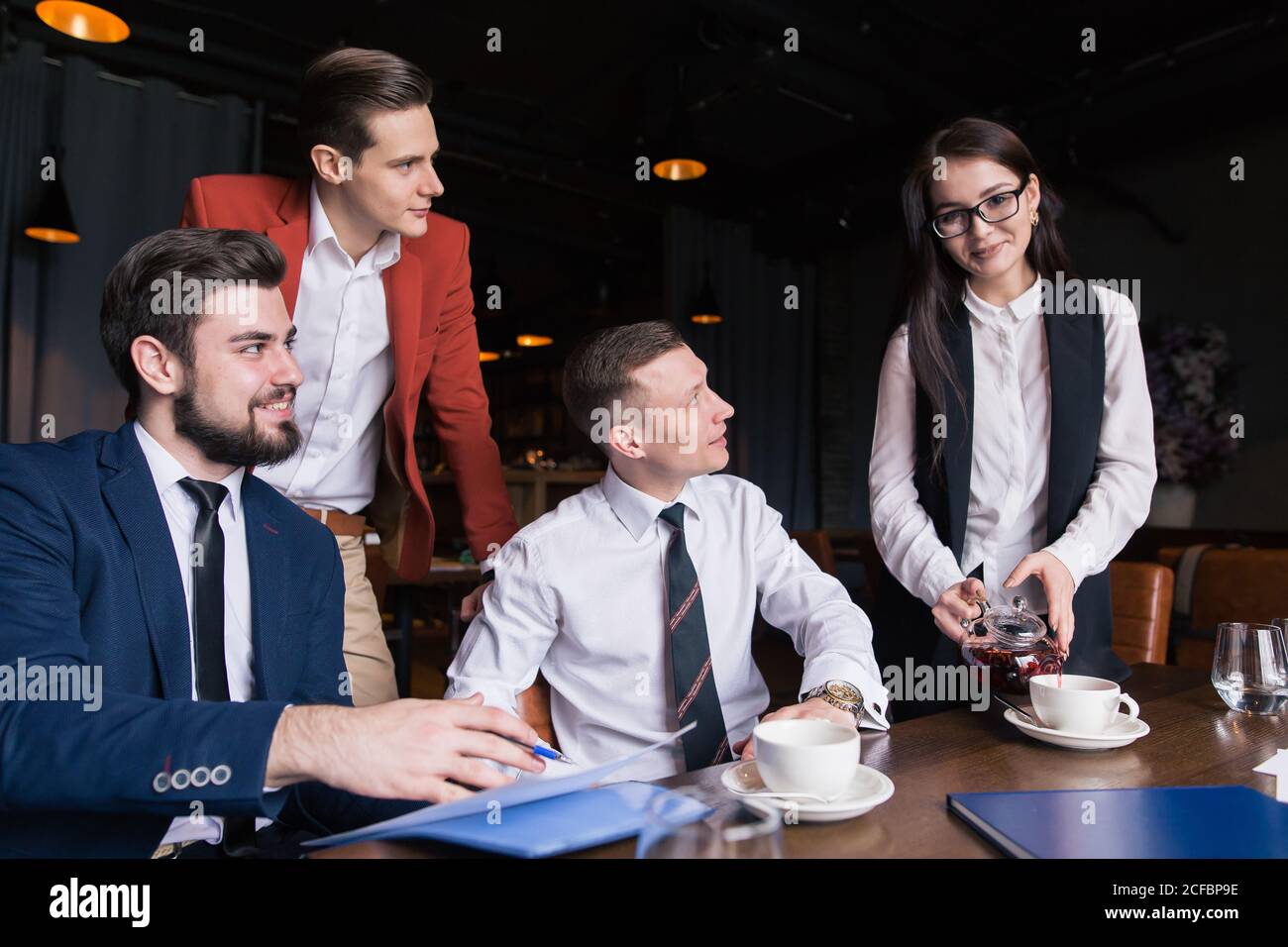 Donna d'affari che versa un po' di tè nel lavoro Foto Stock