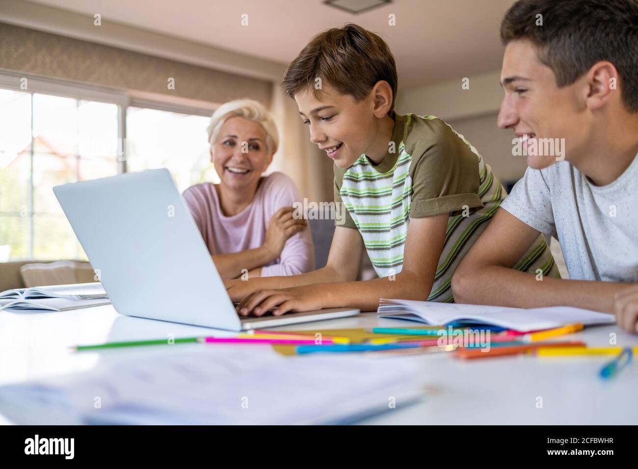 Madre che aiuta i suoi figli a fare i compiti a casa Foto Stock