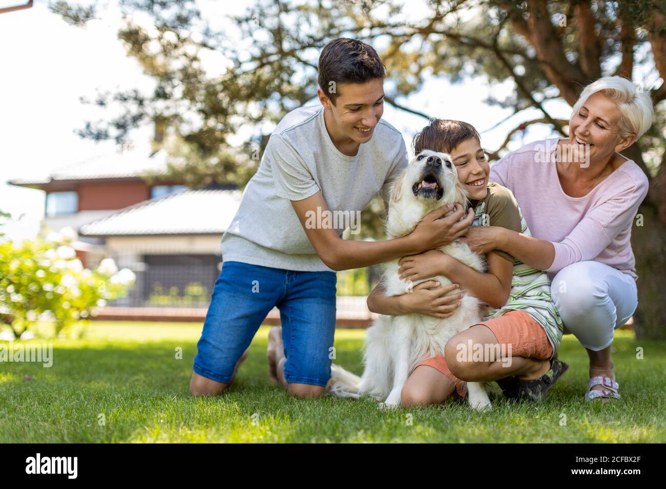Madre e i suoi figli che giocano con il loro cane nel giardino Foto Stock