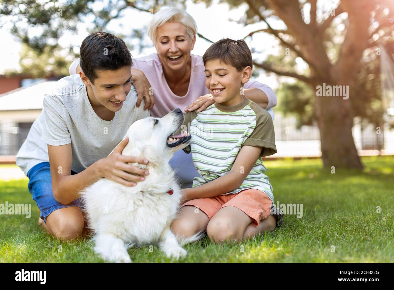 Madre e i suoi figli che giocano con il loro cane nel giardino Foto Stock