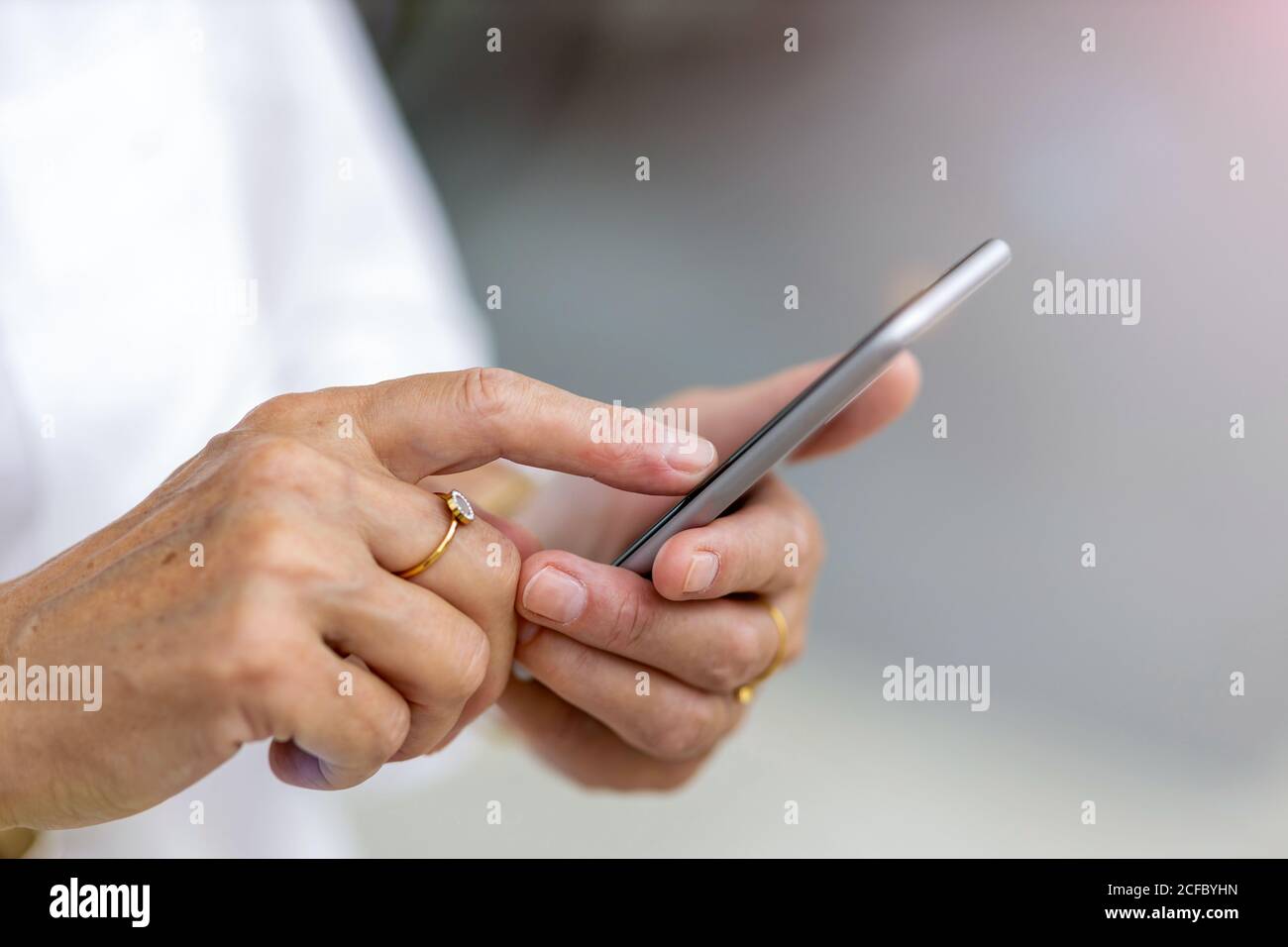 Le mani di una donna anziana che tiene uno smartphone Foto Stock
