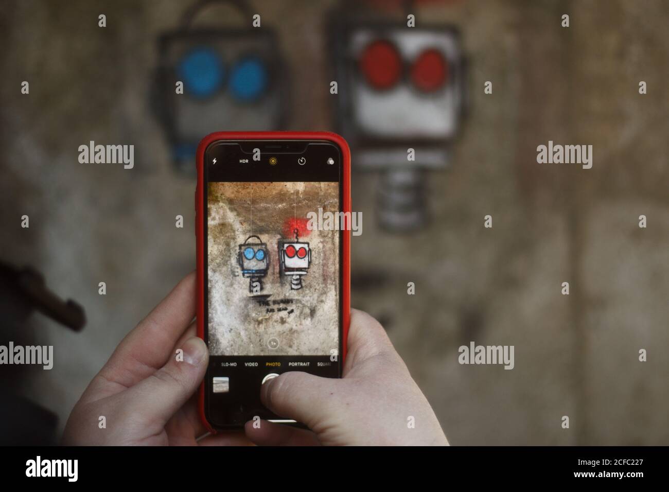 Robot Graffiti su parete in cemento preso attraverso un telefono cellulare Foto Stock