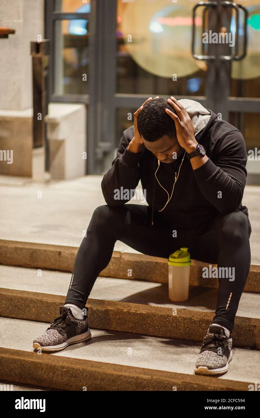 giovane uomo seduto a terra di notte, runner in pausa. Foto Stock
