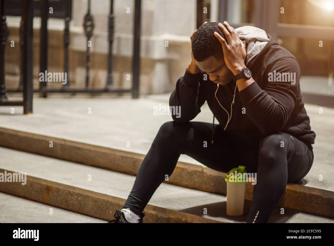 giovane uomo seduto a terra di notte, runner in pausa. Foto Stock