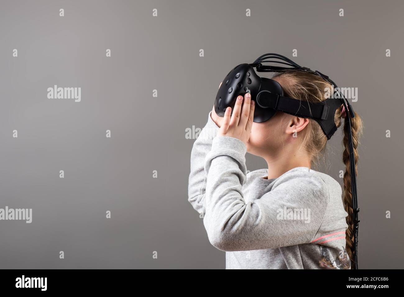 Bambino con cuffia per realtà virtuale seduto dietro il tavolo all'interno a. casa Foto Stock