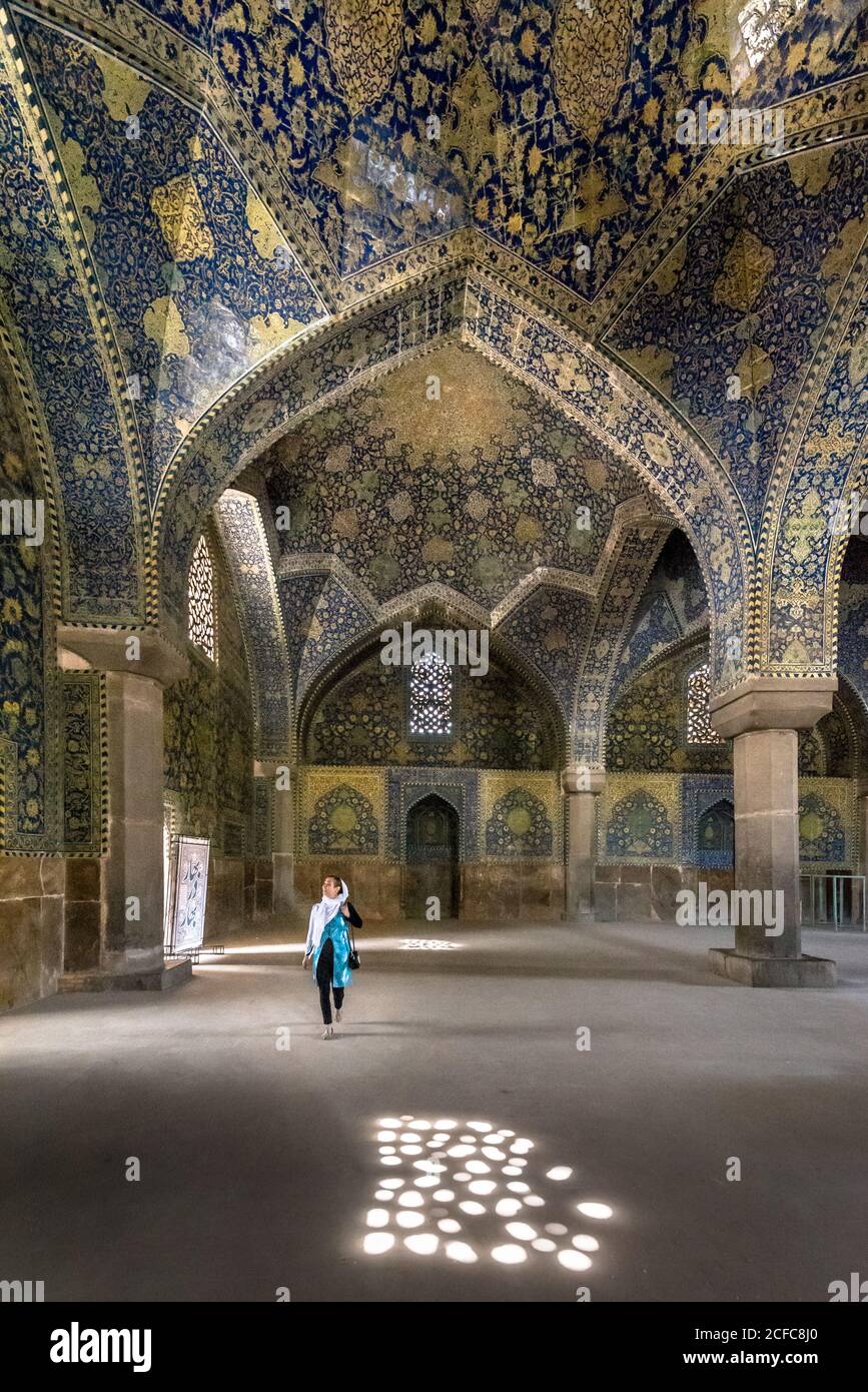 Donna musulmana in piedi nella maestosa moschea iraniana con pareti ornamentali coperto da mosaico colorato e vetrate colorate Foto Stock