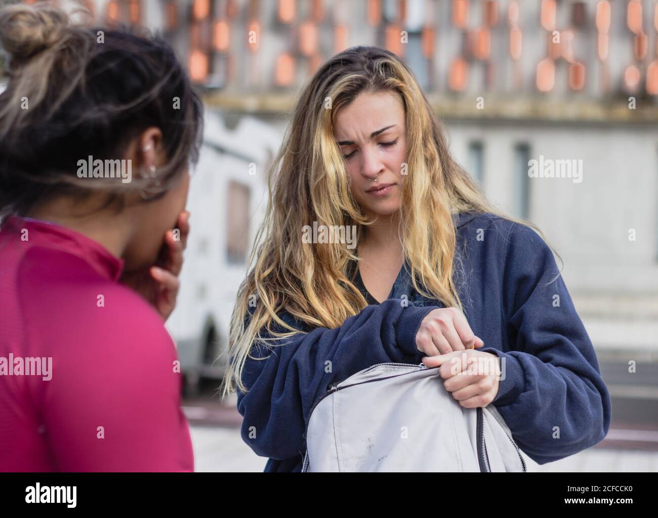 Sportivo femminile stanco con zaino in piedi sul campo sportivo insieme alla ragazza etnica dopo l'allenamento Foto Stock