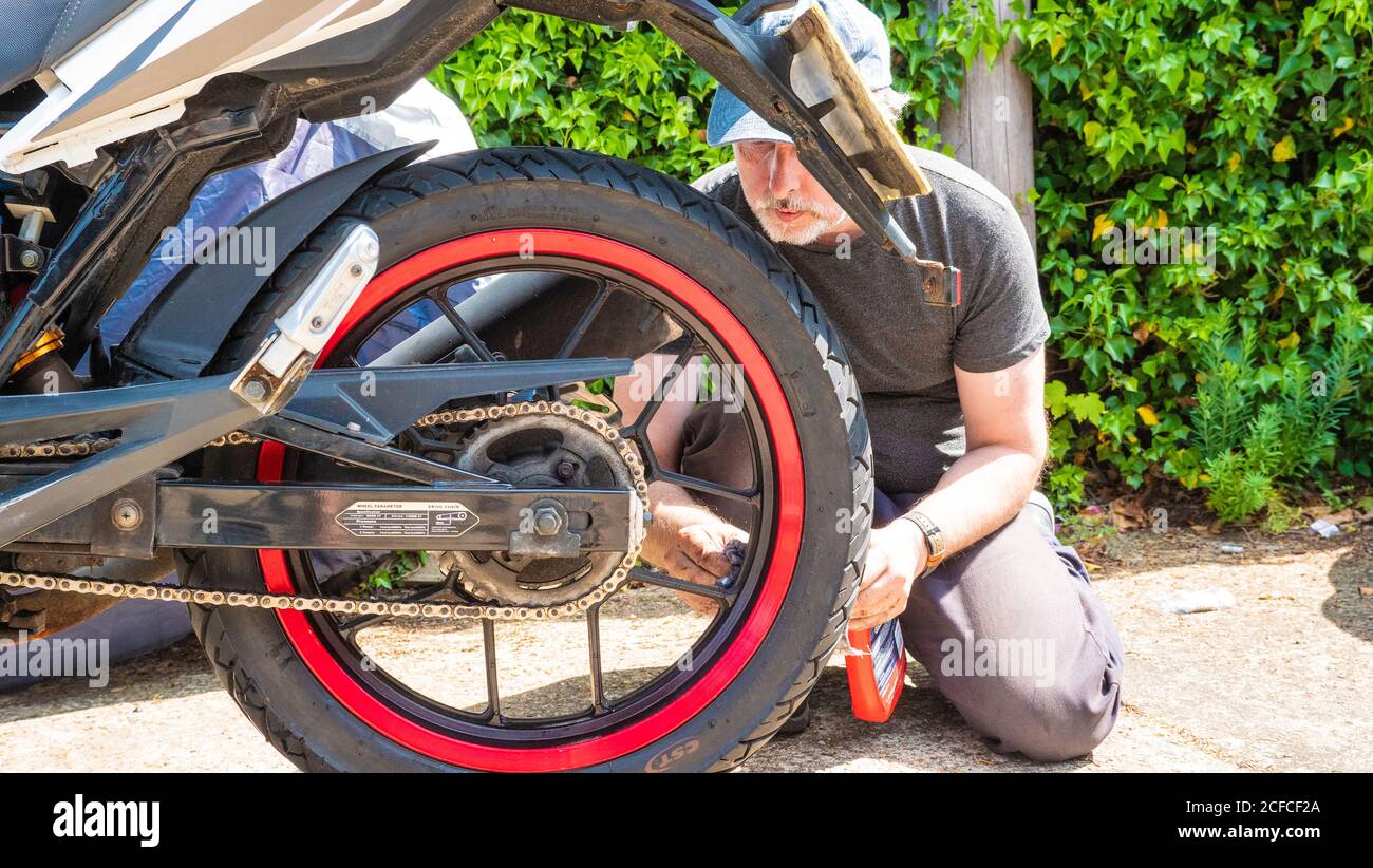 Un uomo che ripara una moto Foto Stock