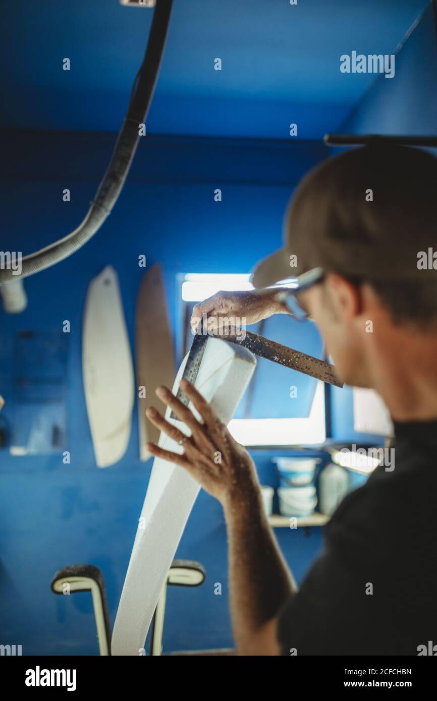 Falegname facendo diligentemente tavola da surf in officina Foto Stock