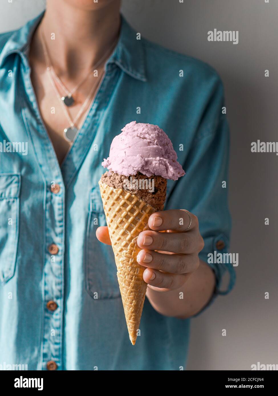 Gelato a mano nel cono. Paletta gelato in cono in mano Donna. Verticale Foto Stock