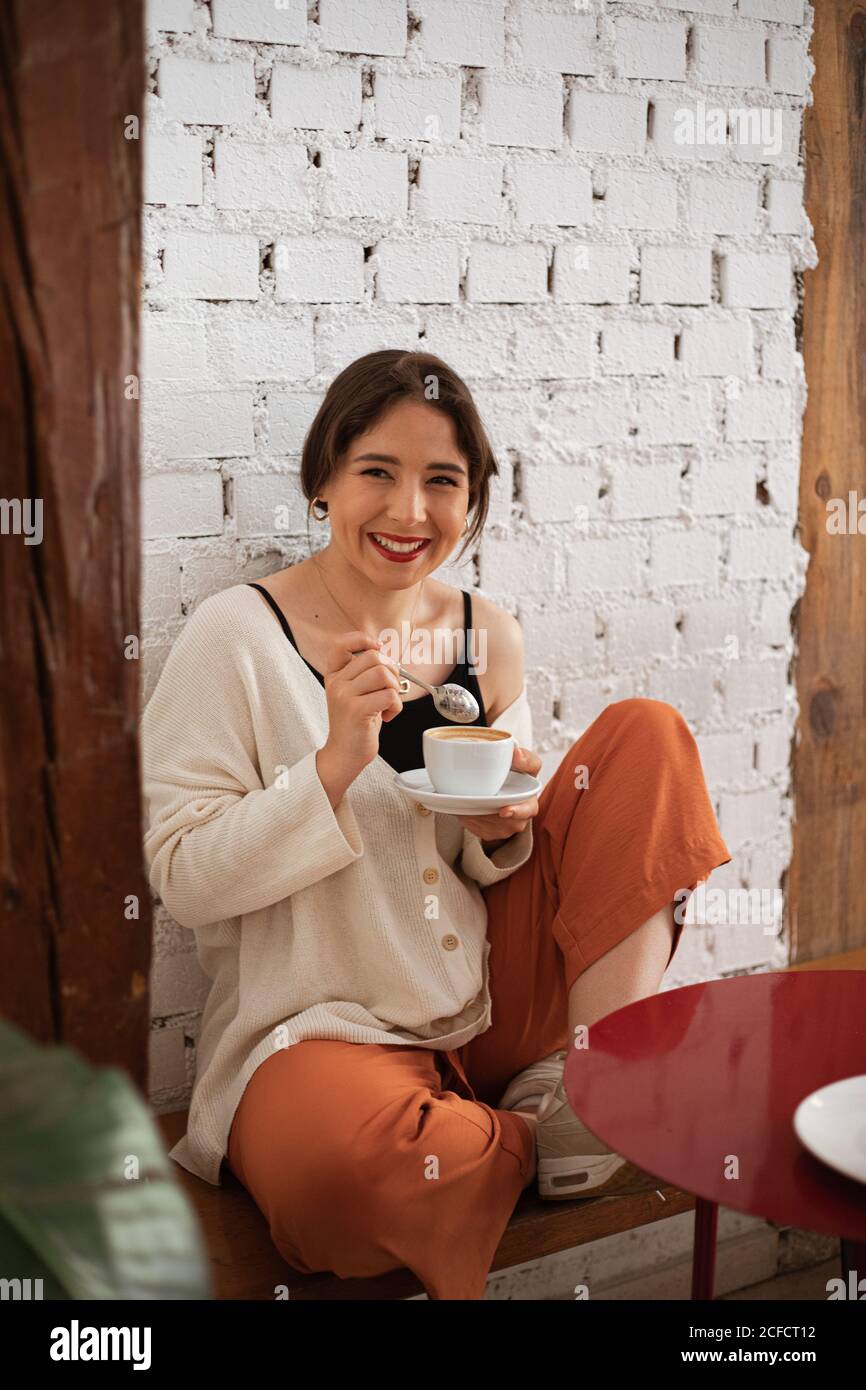 Donna pacifica bere caffè mentre riposa a casa Foto Stock