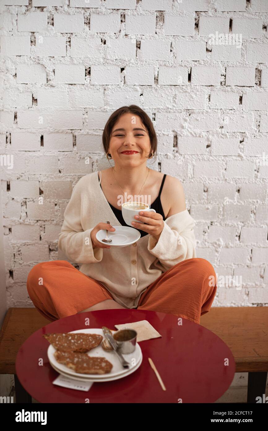 Donna pacifica bere caffè mentre riposa a casa Foto Stock