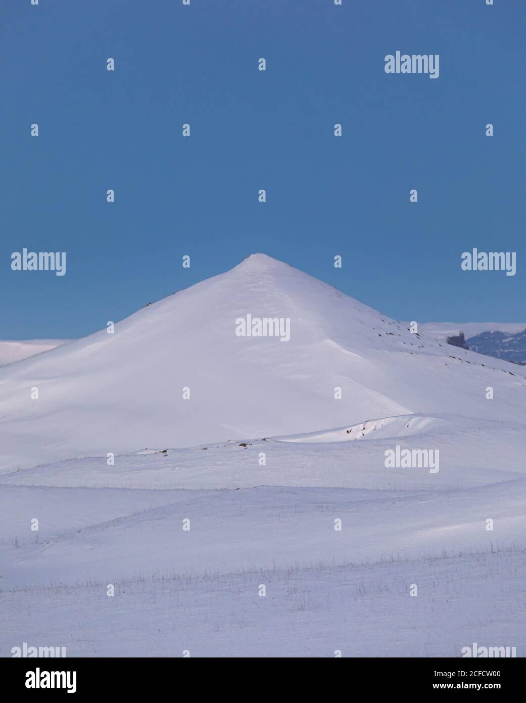 Paesaggio invernale minimalista con collina innevata e valle sotto la limpida Cielo blu in un giorno di sole in Islanda Foto Stock