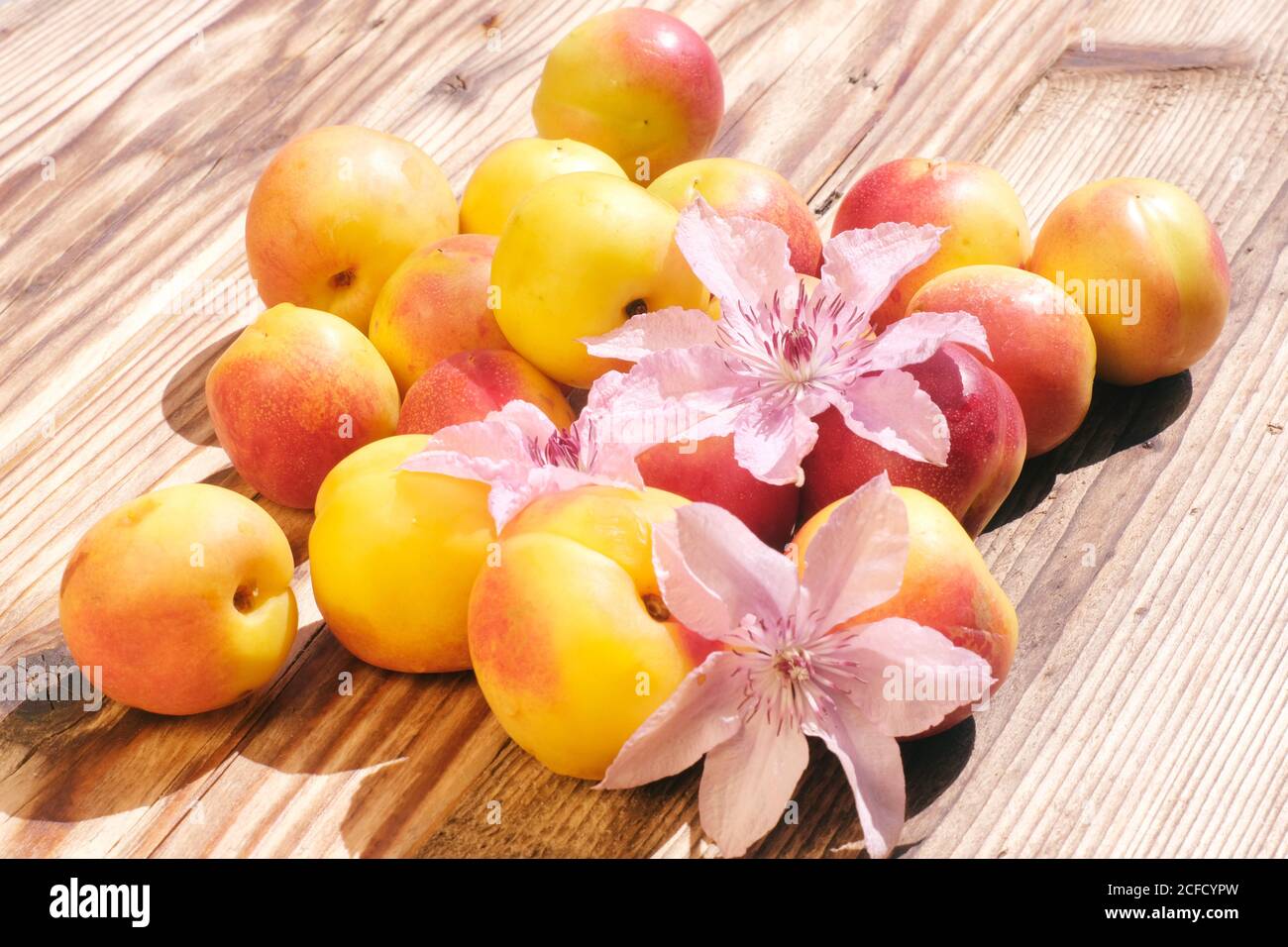 Frutta nettarina e fiori di Clematis su un tavolo di legno Foto Stock