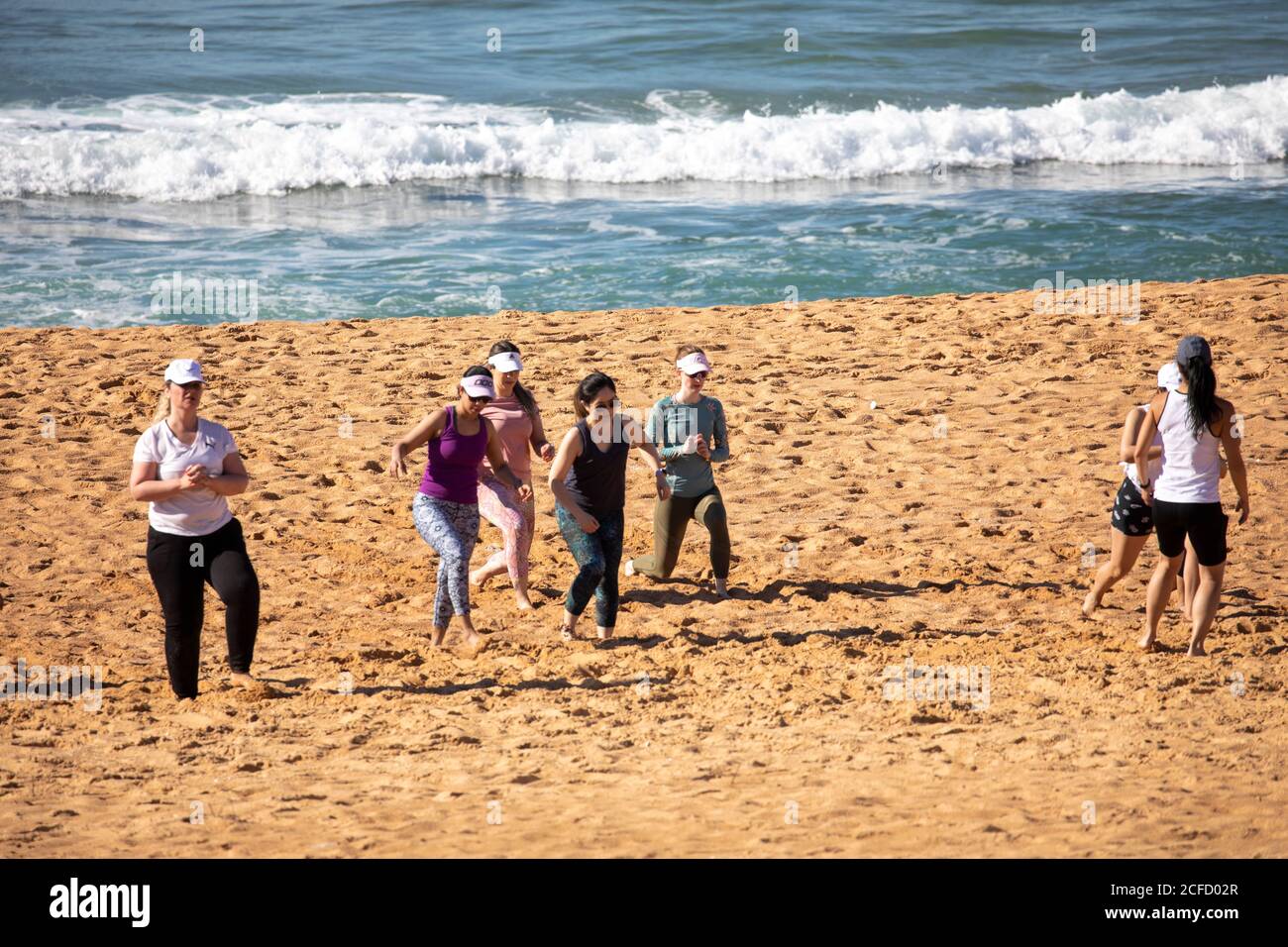 Le donne australiane si allenano e si allungano sulla spiaggia di Sydney a Narrabeen, NSW, Australia Foto Stock