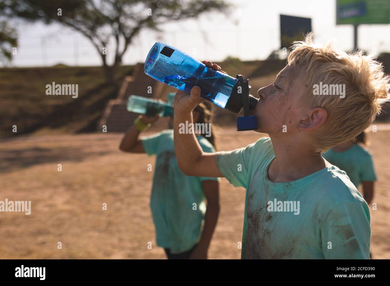 Gruppo di ragazzi che bevono acqua in un campo di stivali Foto Stock