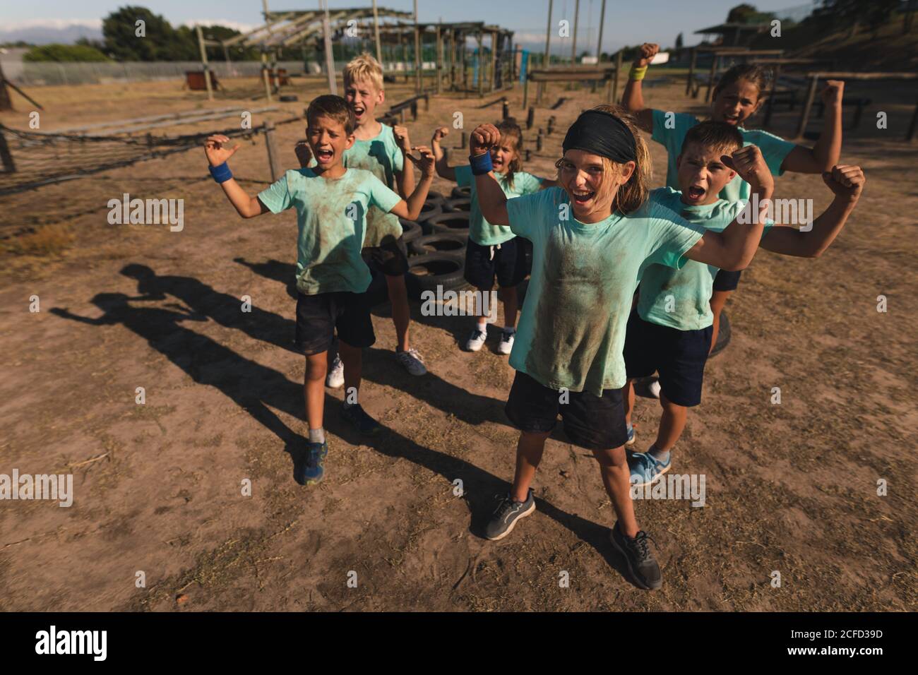 Gruppo di bambini che flettono i loro bicipiti in un campo di stivali Foto Stock