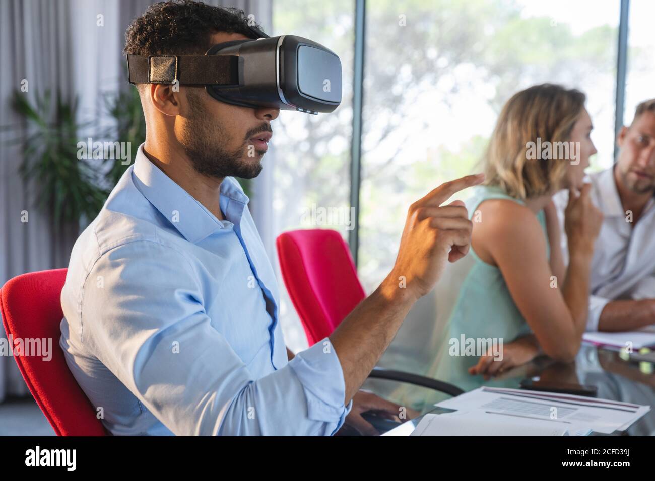 Giovani uomini d'affari che utilizzano cuffie per la realtà virtuale in un ufficio moderno Foto Stock