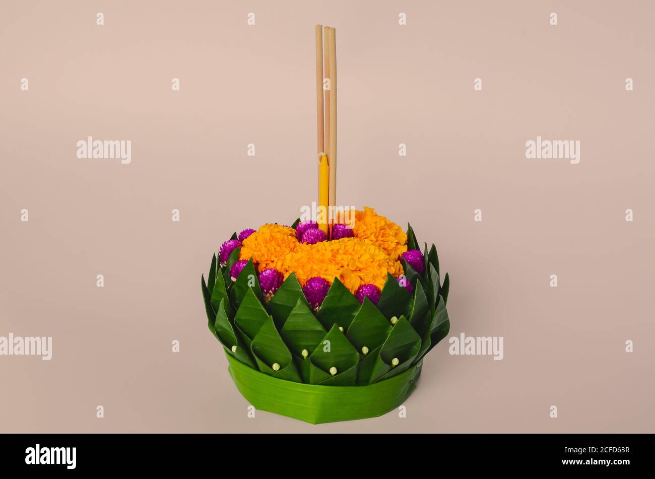 Banana foglia Krathong che hanno 3 bastoni incenso e candela decora con fiori per la Thailandia luna piena o Loy Krathong festival su sfondo rosa. Foto Stock