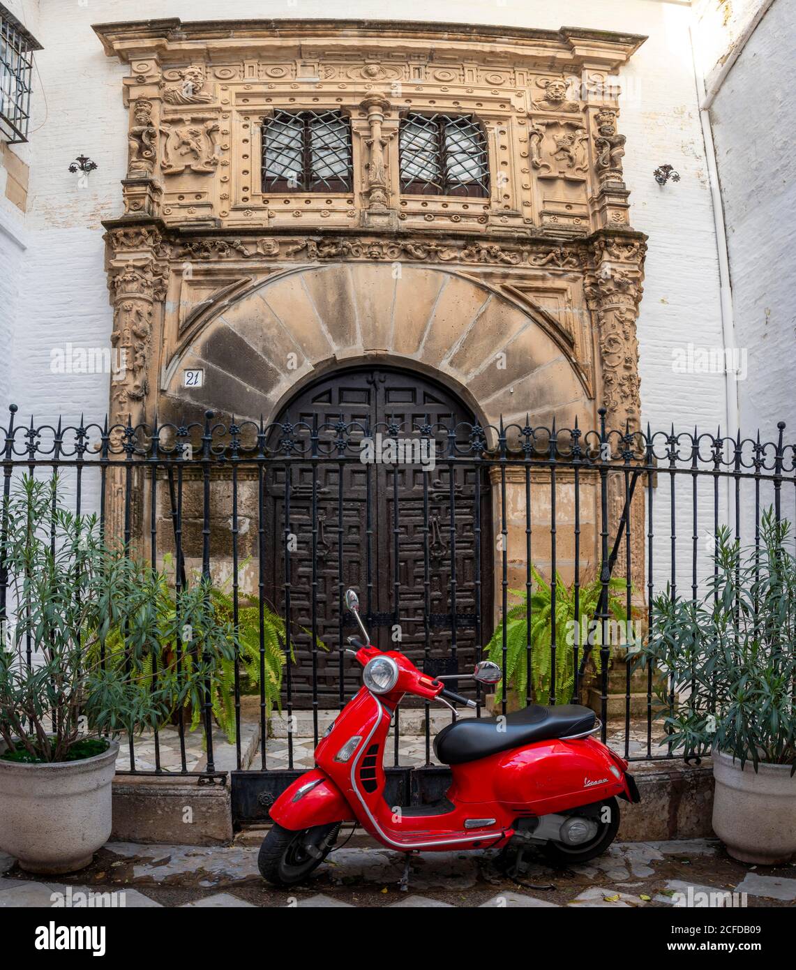 Scooter rosso, Piaggio Vespa, di fronte ad una porta d'ingresso, Santa Cruz, Siviglia, Andalusia, Spagna Foto Stock