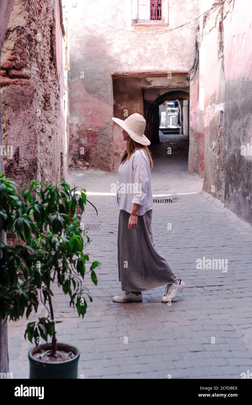 Marrakech, Marocco - Ottobre, 23, 2018: Vista laterale di una donna senza volto turista in cappello elegante camicia e gonna a piedi al vicolo a dondolo Foto Stock