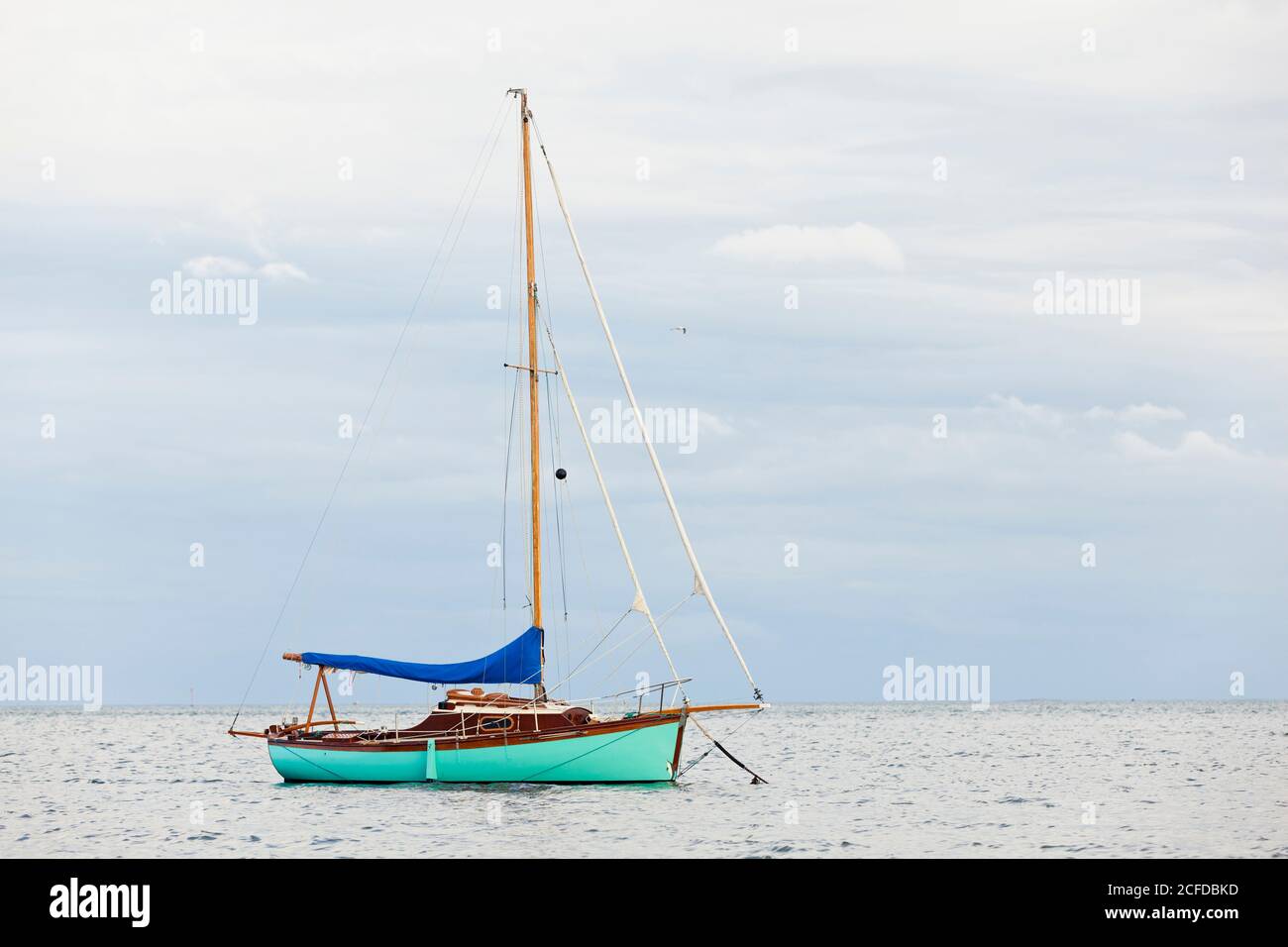 Una barca a vela è ancorata in un mare liscio. Non lontano dalla città portuale di Saint Vaast la Hague. Penisola di Cotentin Foto Stock