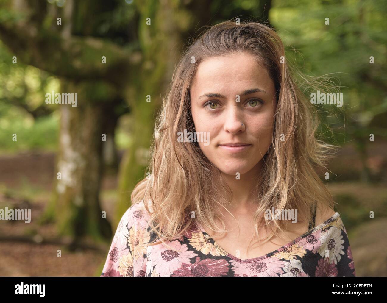 Ritratto di bella donna sognante con occhi verdi guardando la fotocamera su sfondo di alberi mossy Foto Stock