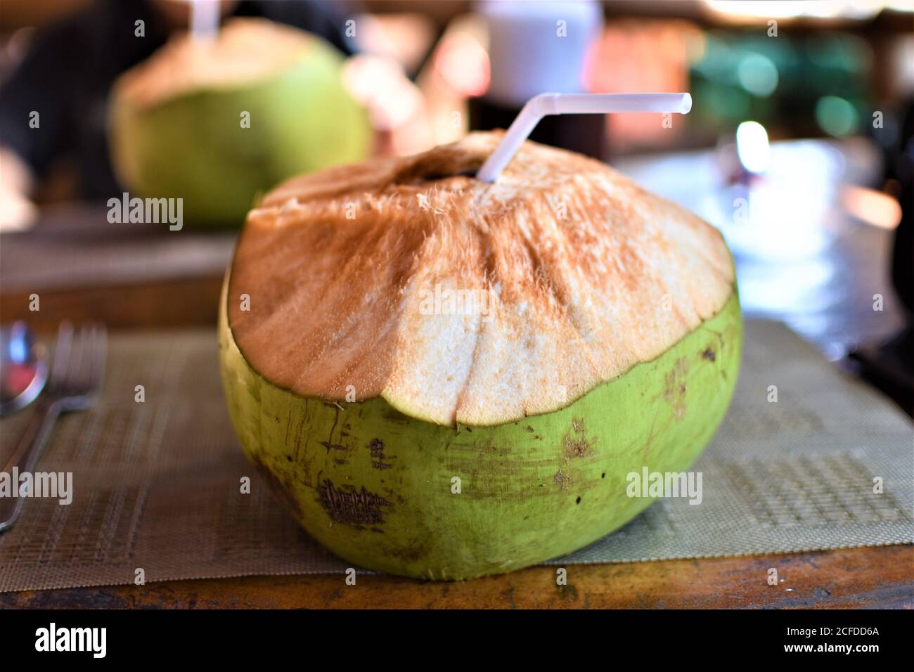 Acqua di cocco fresca servita nella conchiglia in un locale ristorante fronte spiaggia Foto Stock